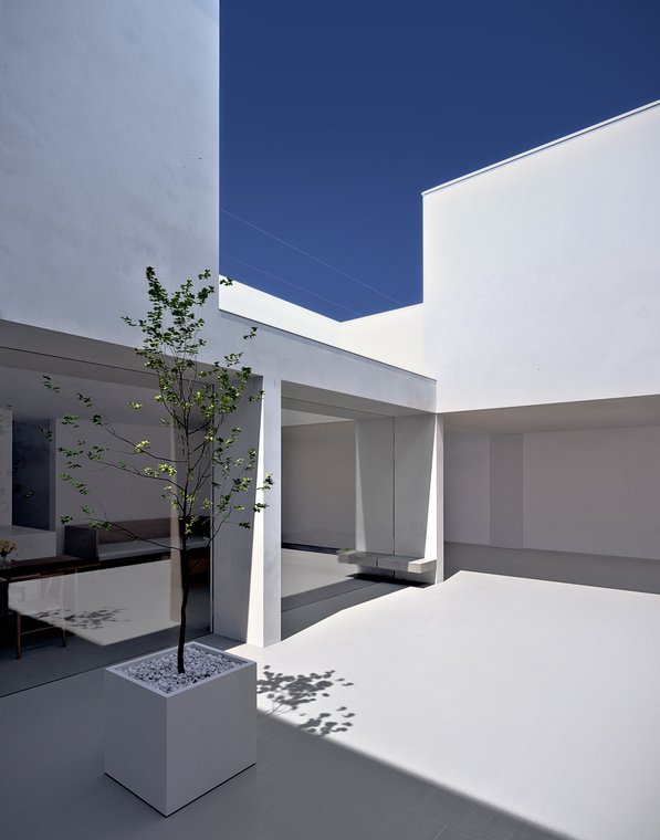 3D απεικόνιση του White Cave House, γαλήλια αυλή με ένα δέντρο σε λευκή γλάστρα, φωτεινή αρχιτεκτονική με ανοιχτά περάσματα.