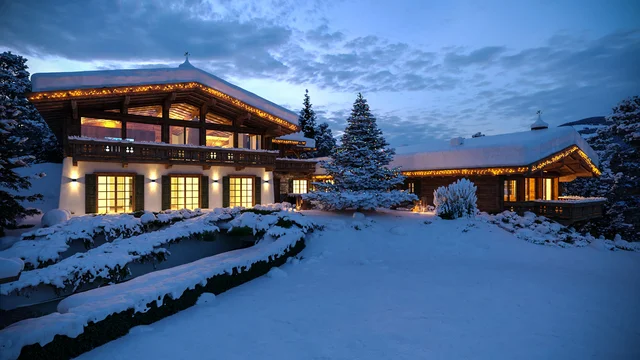 3D απεικόνιση ενός πολυτελούς σαλέ στο Κιτσμπούχελ, καλυμμένου με χιόνι και φωτισμένου με ζεστά γιορτινά φώτα στο λυκόφως, δημιουργία της gmsvision.